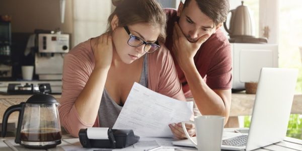 young-caucasian-family-having-debt-problems-not-able-to-pay-out-their-loan-female-in-glasses-and-brunette-man-studying-paper-form-bank-while-managing-domestic-budget-together-in-kitchen-interior